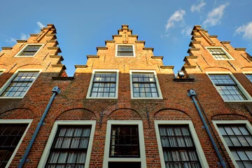 Deurstickers Haarlem, Netherlands - MAY 24, 2022: Row of three houses with stepped gables in Groot Heiligland street in old town. Low angle view. © Nigel Wiggins