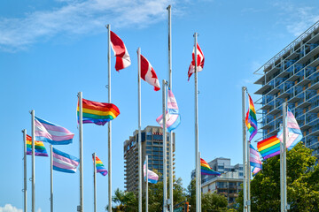 Gay Pride and Trans Pride Flags in Vancouver. Rainbow colored Gay Pride, Trans Pride, and Canadian Flags flutter in the wind beside English Bay in Vancouver’s West End Neighborhood. British Columbia,
