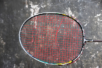 Old badminton racket with broken strings on wall background