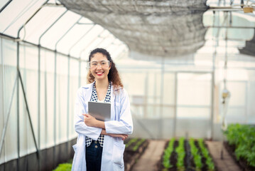 Portrait of Woman agricultural researcher holding tablet while working on research at plantation in industrial greenhouse