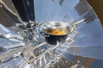 Cooking with sun energy, parabolic solar oven in the middle of cooking a dish thanks to solar energy - Powered by Adobe
