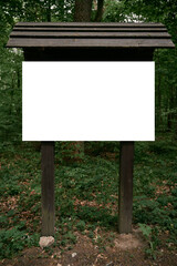Empty sign in the forest. Mock up of an informational wooden board in the woods