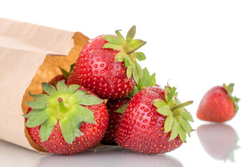 Several berries of ripe organic strawberries with a paper bag, close-up, isolated on a white background.