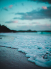 Caribbean white sand beach at sunrise with waves crashing and warm light on a cloudy morning in Tulum 