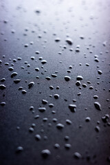 Selective focus on water drops on black synthetic fabric.