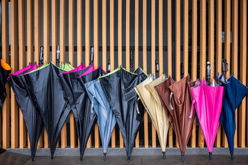 Wet umbrellas leaning on wooden wall for drying.