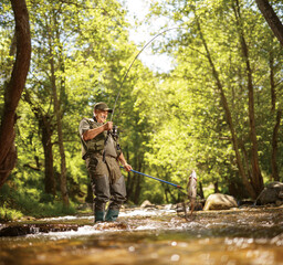 Naklejka premium Fisherman catching a carp fish with a rod and a net