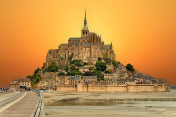 Scenic view of the island - fortress Mont Saint Michel with a Mont-Saint-Michel Abbey against the backdrop of a dramatic sunset at low tide of the Atlantic Ocean. Department Manche, Normandy, France © Artur