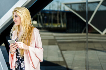 happy blonde young woman outdoor using her mobile phone