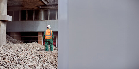 Demolition of the building. A construction worker stands in a signal vest on a pile of garbage....