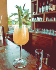 Tropical orange cocktail with pineapple in wooden bar at sunset in Tulum bar on a sunny day