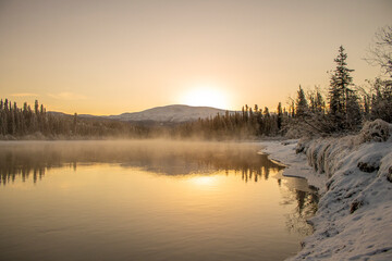 Sunrise on a foggy and snowy lake in Yukon, Canada