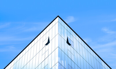 Fototapeta na wymiar Manipulation techniques image of light reflection on surface of modern glass office building against blue sky in symmetry and low angle view