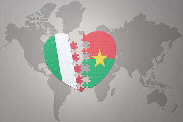 puzzle heart with the national flag of burkina faso and italy on a world map background. Concept.