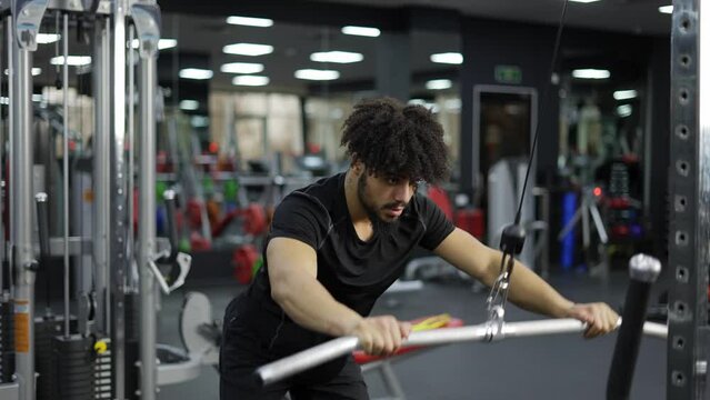 Young man exercising on lateral pull at gym for the back mucles, slow motion