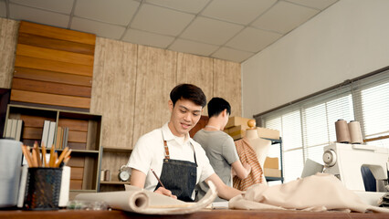 Young LGBTQ Asian Men Small Business Partner,The assistant is asking the shopkeeper for advice on how to sew needles on the fabric,Professional Design clothes to sell online.