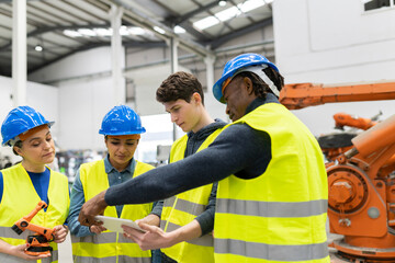 multiracial workers in a robotic factory, engineers discussing car parts in the factory