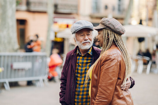 multiracial senior couple, african woman and grey-haired asian man, walking in the city