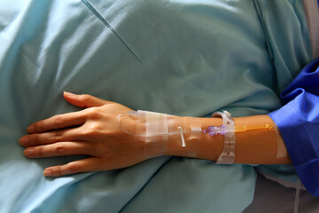 Close up the patient's hands and arms are giving the saline solution on bed with copy space. Healthy, Medicine or Medical and injection in vintage tone. People cure sickness and fever at hospital.