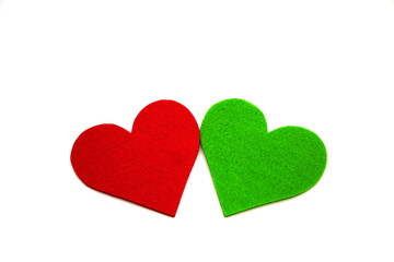 Red and green colored heart shapes made of felt with decorative pins, shot on white.