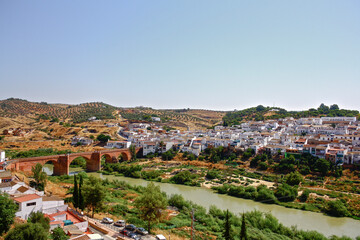 Fototapeta premium Wide view of Montoro, Andalusia, Spain, with its traditional white houses, the medieval bridge over the Guadalquivir river and the plantations in the background