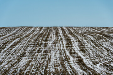 The plowed field is covered with snow and ice. The threat of crop destruction and starvation of the population.