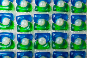 Capsules for washing laundry detergents for washing clothes in the washing machine background. The...