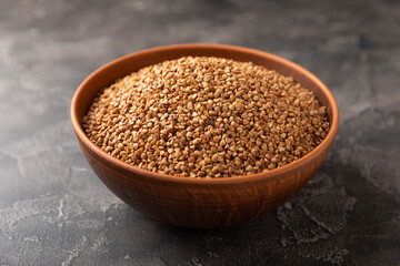 Buckwheat in a bowl on a black textured marble background. Raw buckwheat. Ingredients for gluten free cereal. Healthy food. Place to copy.