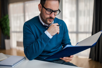 Serious businessman analyzing documents while working at office desk