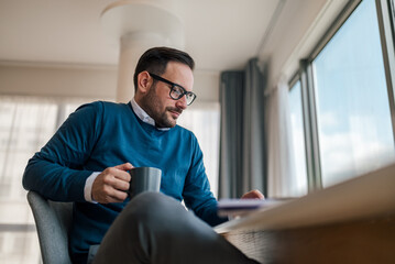 Young businessman having coffee while working at office desk