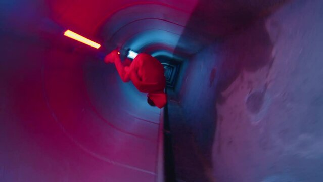Camera roll of parkour athlete running through dark underground tunnel with neon light and performing side flip