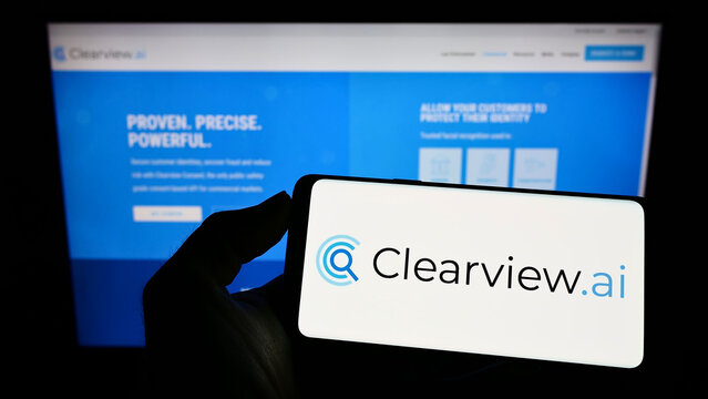 Stuttgart, Germany - 05-26-2022: Person holding cellphone with logo of facial recognition company Clearview AI Inc. on screen in front of business webpage. Focus on phone display.