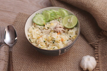 Pork Fried Rice, Chinese Style Fried Rice in a Bowl with Cucumber and Lemon Served on a brown wooden table.