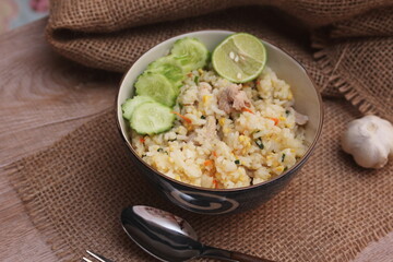 Pork Fried Rice, Chinese Style Fried Rice in a Bowl with Cucumber and Lemon Served on a brown wooden table.