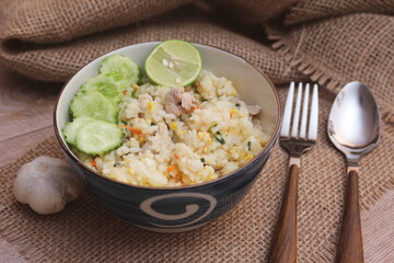 Pork Fried Rice, Chinese Style Fried Rice in a Bowl with Cucumber and Lemon Served on a brown wooden table.