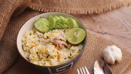 Pork Fried Rice, Chinese Style Fried Rice in a Bowl with Cucumber and Lemon Served on a brown wooden table.