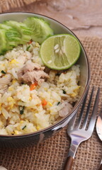 Pork Fried Rice, Chinese Style Fried Rice in a Bowl with Cucumber and Lemon Served on a brown wooden table.
