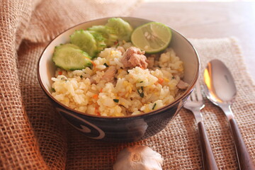 Pork Fried Rice, Chinese Style Fried Rice in a Bowl with Cucumber and Lemon Served on a brown wooden table.