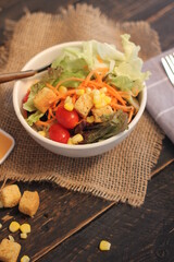 Caesar salad in white bowl served with Caesar dressing. on a black wooden table.