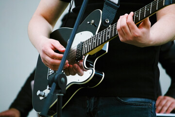 Fototapeta na wymiar Black chrome-plated electric guitar and guitarist's hands close-up