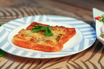 Fried bread with minced pork spread with cucumber dipping sauce on a wooden table.