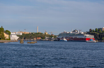 Panorama view over the bay Stockholms Ström in evening light with the district Södermalm and cruise ships and island with a castle and brick building a sunny evening in Stockholm