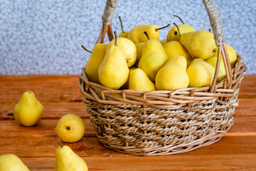 Basket with ripe juicy yellow dream pears close-up wooden table