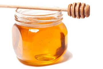 Honey dripping from honey dipper in glass jar. Healthy food concept