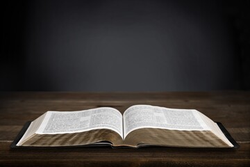 Open Christian bible book on old wooden table.