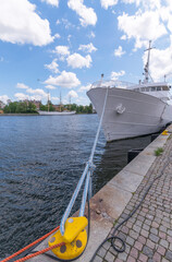 Fototapeta na wymiar Fore of a commuting and theatre boat moored at the pier Skeppsbron and the newly restored hostel ship af Chapman in the back ground a sunny summer day in Stockholm