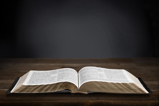 Open Christian bible book on old wooden table.