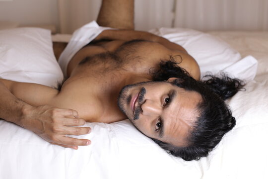 Attractive Hispanic man shirtless in bed