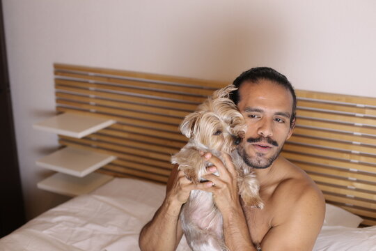 Cute man in bed with his Yorkshire Terrier