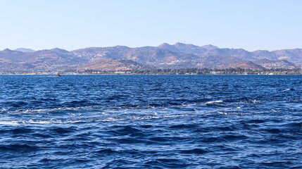 Fototapeta na wymiar Blue sea with waves. Beautiful coast with mountains